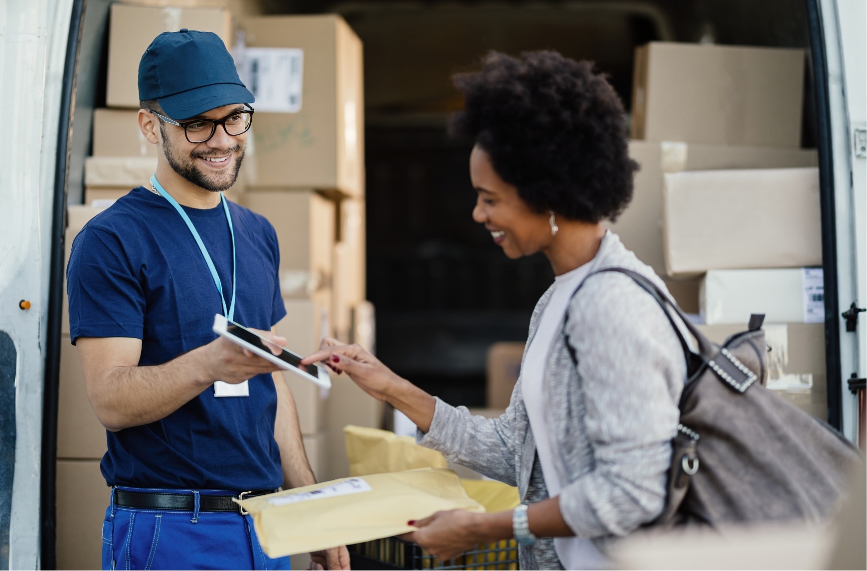 A delivery driver asks a customer to sign for a parcel.