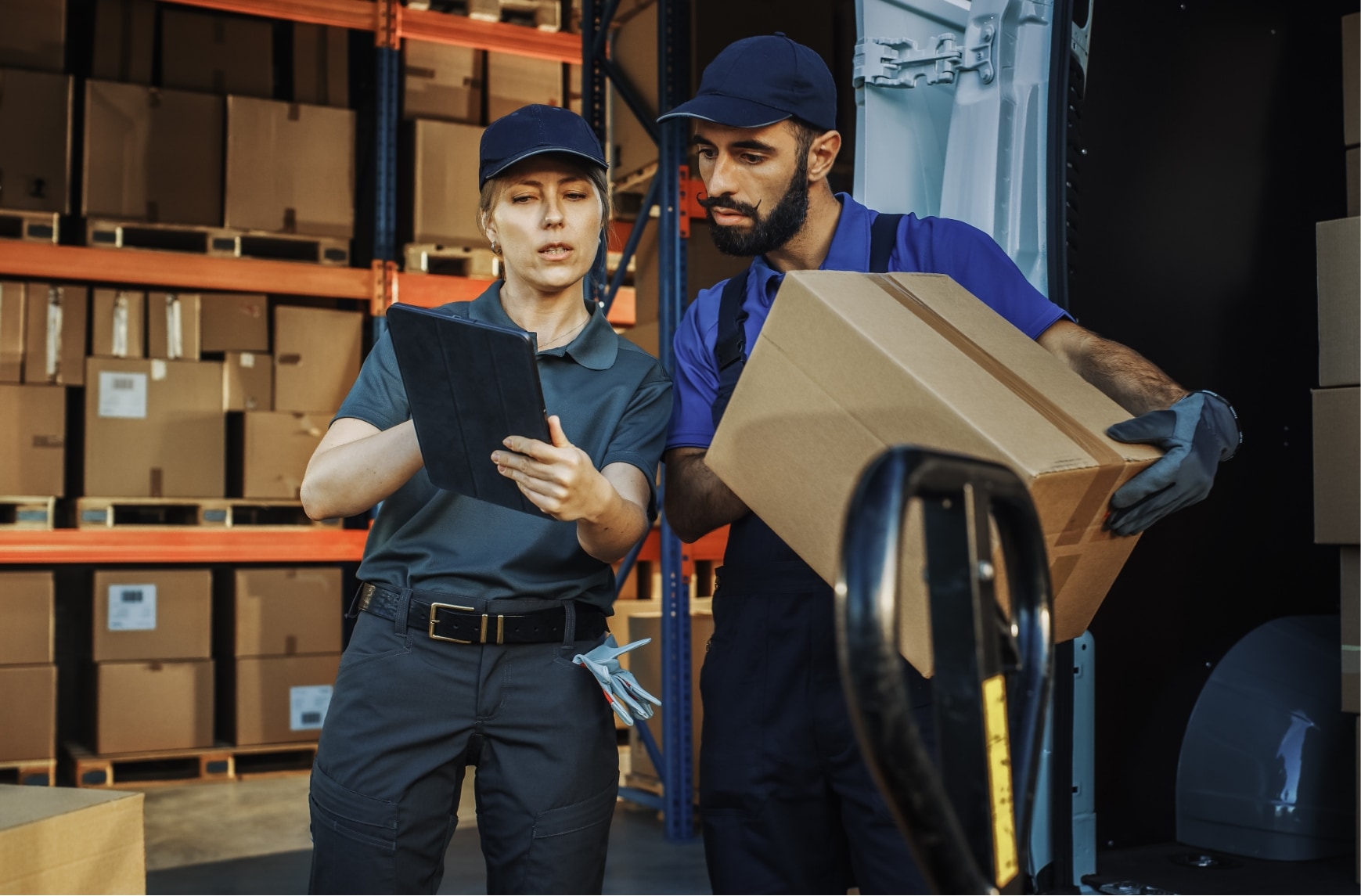 Deux personnes chargent des marchandises dans un véhicule devant un entrepôt.