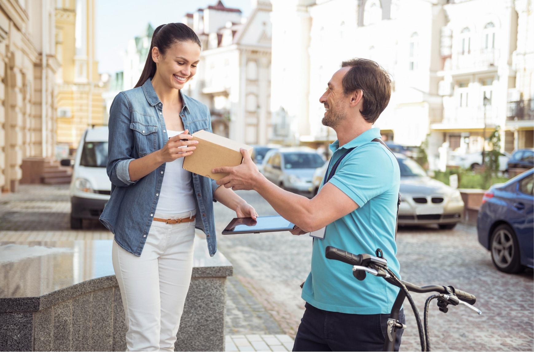 Un chauffeur-livreur à vélo donne un colis à une femme en ville.