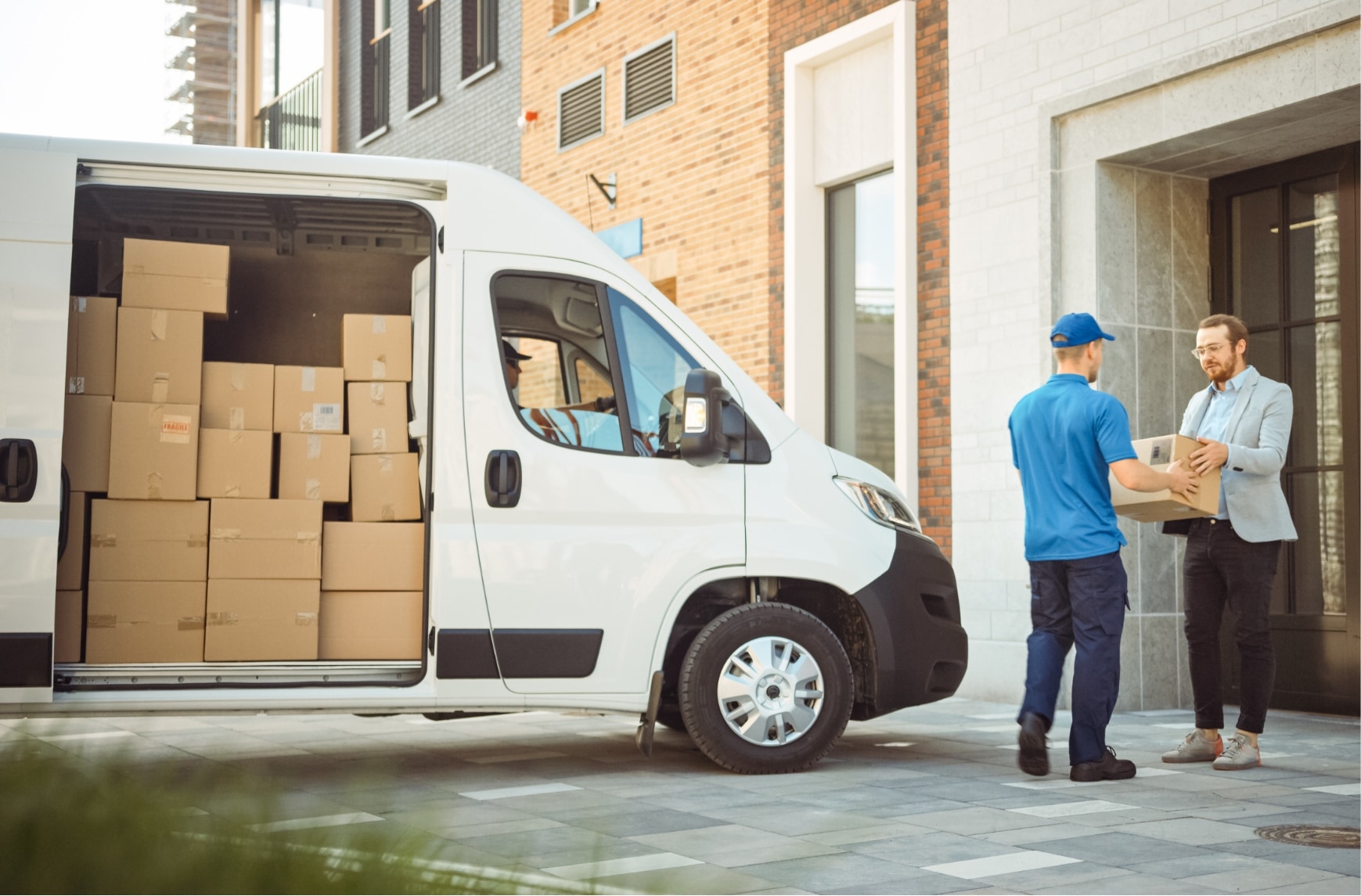 A deliveryman gives a man a parcel.